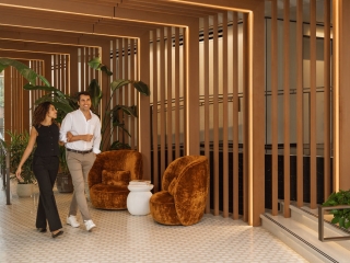 A Man And Woman Standing In Front Of A Glass Wall With Plants