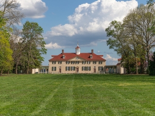 A Large Building With A Lawn In Front Of It With Mount Vernon In The Background