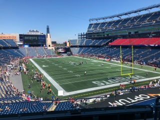 A Football Stadium With A Field And A Crowd Of People With Gillette Stadium In The Background