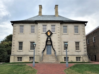 A Large Building With A Clock On The Front With Carlyle House In The Background