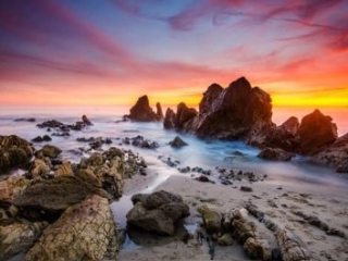A Rocky Beach With A Sunset