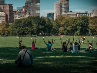 A Group Of People In A Field With A City In The Background