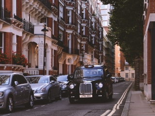 Black taxi driving down the street in London