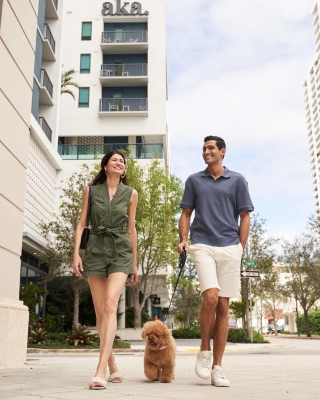 A Man And Woman Walking A Dog